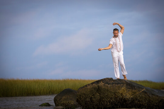 Man wearing white dancing in the beach on Cape Cod during the pi