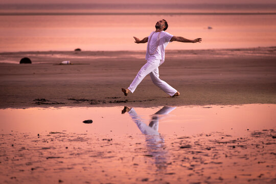 Man wearing white dancing in the beach on Cape Cod during the pi