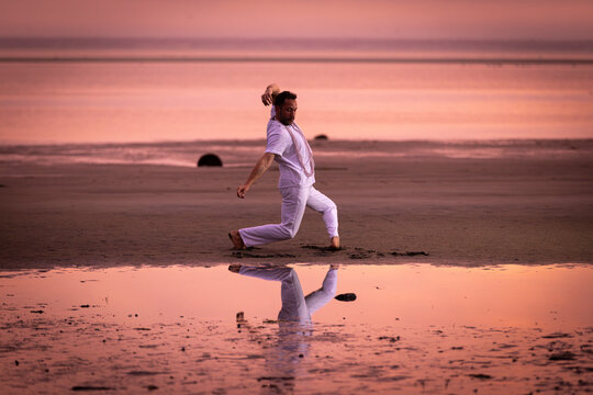 Man wearing white dancing in the beach on Cape Cod during the pi