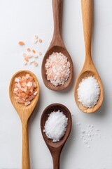 Flat lay of Celtic Salt vs other salt types in wooden spoons on light wood background, comparison scene