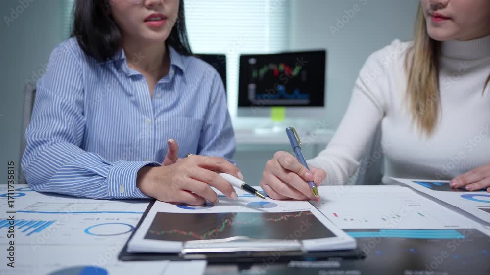 Poster two businesswomen are discussing and analyzing financial charts and graphs, pointing at specific dat