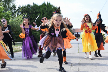 Naklejka premium Happy Halloween children in costumes collect sweets on the street