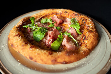 Pizza Perfection: A tantalizing close-up showcases a freshly baked pizza, adorned with vibrant greens and savory slices, presented on a rustic platter, promising a culinary delight.