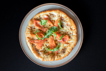 Gourmet Salmon Pizza on Plate: A tantalizing overhead shot of a freshly baked pizza featuring succulent salmon slices, vibrant green arugula, and a golden-brown crust.