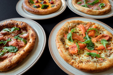 Gourmet Pizza Feast: A delicious array of gourmet pizzas, each adorned with fresh toppings, served on individual plates, inviting to savor the flavors.