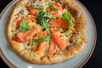 Salmon Pizza Delight: A culinary creation features a golden-crusted pizza adorned with savory salmon slices and vibrant fresh green accents, creating a mouthwatering experience.