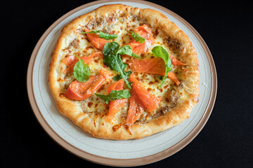 Smoked Salmon Pizza: A top-down view of a delicious smoked salmon pizza, topped with fresh basil and placed on a ceramic plate, offers a tantalizing culinary scene.