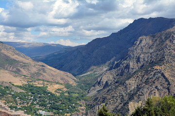 Fototapeta premium A girl in the mountains. A village and beautiful nature. Houses surrounded by forests.