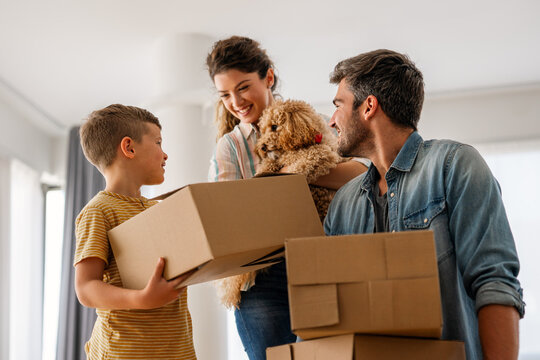 Smiling man and woman enjoy unpacking with child moving to own home. Rent, mortgage concept