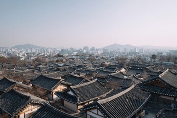 Rooftops quilt the Korean village under a gentle mist, celebrating Chuseok with whispers of ancient tales and lantern-lit evenings