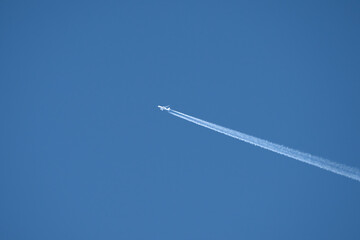 twin engined jet liner aircraft with contrails, in flight at high altitude, clear blue sky