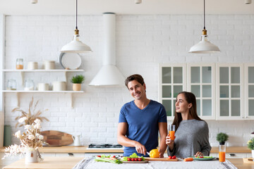 Couple in the kitchen preparing a dish from healthy vegetables, chatting happily, balanced nutrition.