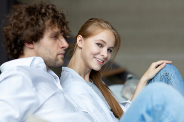 Affable close-up image of a cheerful young man and woman in a living room, conveying uplifted emotional state