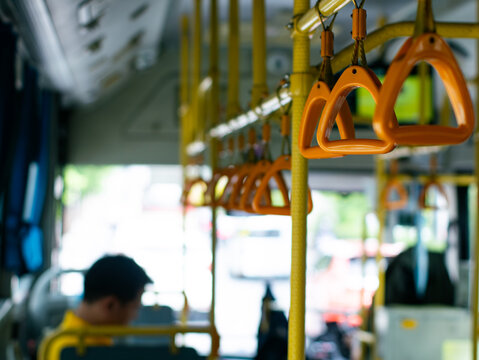 Passenger handholds and grab bars inside public transportation bus or train - safety support handles for commuters in urban transit vehicle.