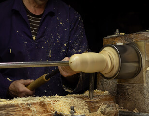 Woodworker in the workshop. Turner working on the lathe. Carpenter's hands making wooden matryoshka doll