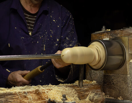 Woodworker in the workshop. Turner working on the lathe. Carpenter's hands making wooden matryoshka doll