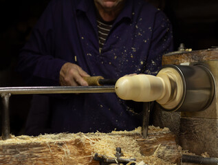 Woodworker in the workshop. Turner working on the lathe. Carpenter's hands making wooden matryoshka doll