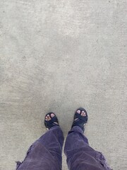 A person standing with sandals on a concrete floor