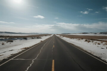 A long straight road stretching through a snowy and open landscape under a clear sky