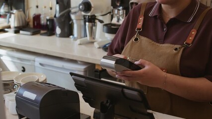 Handheld shot of smiling female multiethnic cafe worker accepting payment from male client using smartphone at counter - Powered by Adobe