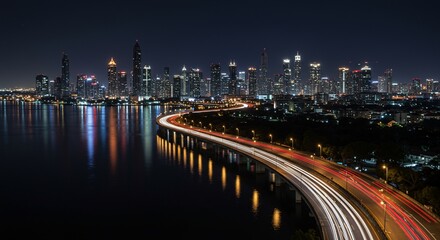 A vibrant city skyline at night featuring a curving highway with dynamic light trails reflecting on the water.