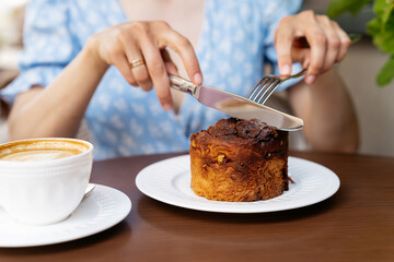 Woman eats a delicious bun with poppy seeds and almonds at breakfast