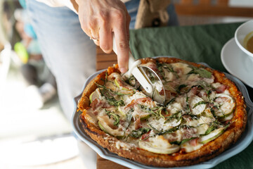 Low carb almond flour pizza being sliced with pizza cutter