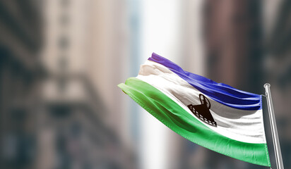 Lesotho national flag waving on street. A beautiful with mast with blur buildings. Lesotho national...