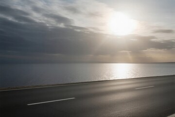 Sunlit Road by the Calm Sea with Cloudy Sky