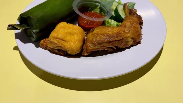 Indonesian food fried chicken and liwet rice served on the table. With tilt up movement