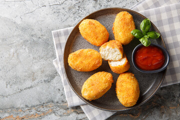 Delicious crispy fried breaded chicken croquettes served with tomato sauce close-up in a plate on the table. Horizontal top view from above
