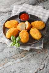 Close-up of Spanish chicken croquettes with ketchup in a plate on a table. Vertical