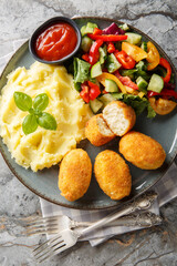 Chicken Croquettes Croquetas de Pollo with mashed potatoes, vegetable salad and ketchup close-up in a plate on the table. Vertical top view from above