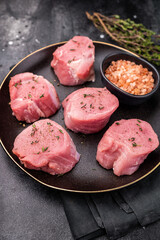 Tender fresh pork medallion, raw tenderloin meat perfect for elevating your dinner table with a touch of culinary finesse. black background. top view