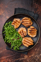 Savory charred pork loin medallion, tenderloin meat showcasing its tender texture and rich flavors after grilling. brown background. top view