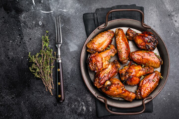 Savory grilled chicken wings smothered in tangy barbecue sauce, the ultimate treat for meat lovers and party enthusiasts. black background. top view