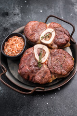 Deliciously braised ossobuco, featuring tender osso buco veal shank and rich marrow, perfect for a gourmet Italian feast. black background. top view