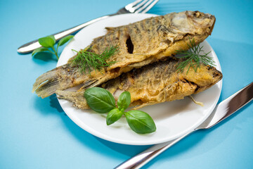 Fried crucian carp with a crispy golden crust on a white plate
