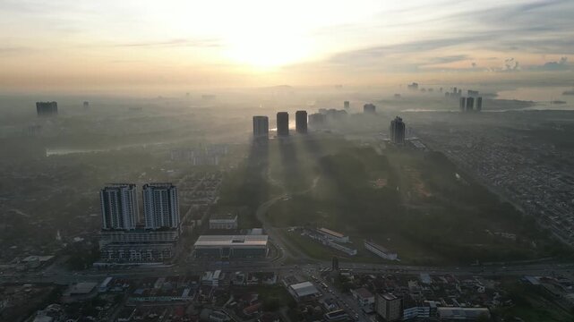 A city skyline with a large building in the middle. The sky is hazy and the sun is setting. Aerial view Larkin, Johor
