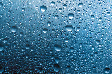 Close-up of blue water droplets on glass, creating an abstract pattern. High-resolution image for design or presentation