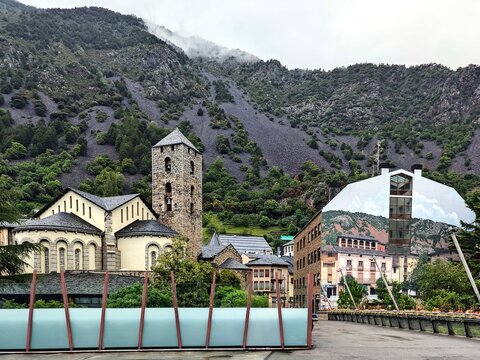 Church of Saint Stephen in Andorra la Vella, Andorra, displaying Romanesque architecture with a stone bell tower and arched windows. Surrounded by lush, green forested hills