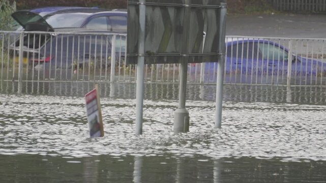 Water Rushing by on Flooded Roundabout with Cars Flooded and Submerged After Heavy Downpour with Road Underwater.