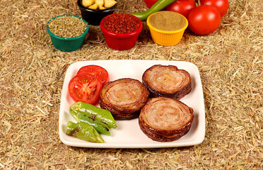 3 kokorech and peppers on a white plate, cut into one portion