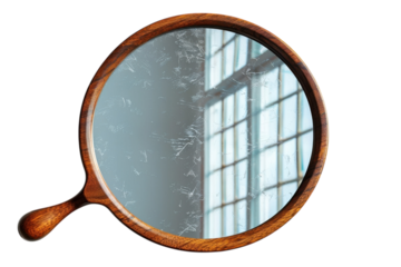 Vintage hand mirror with a wooden frame reflects a window creating a unique antique aesthetic look on transparent background