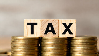 TAX text displayed on wooden blocks placed over stacked gold coins