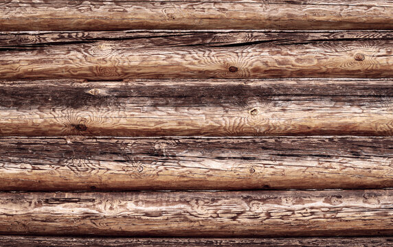 Abstract wooden background from logs. A wall made of old logs with natural patterns on the trunks. The logs are positioned horizontally to the background. Copy space.