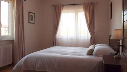 Spacious bedroom with a double bed, sheer curtains, and soft lighting.