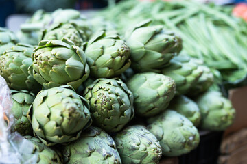Fototapeta premium Pile of fresh artichokes laid out on counter of greengrocer shop closeup