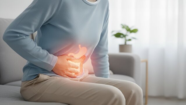 A woman on a couch with glowing digestive overlay symbolizing discomfort, constipation, constipation relief, laxatives