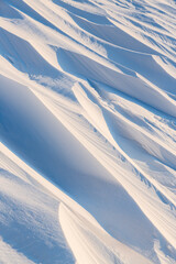 Snow texture. Wind sculpted patterns on snow surface. Wind in the tundra and in the mountains on the surface of the snow sculpts patterns and ridges (sastrugi). Arctic, Polar region. Winter background
